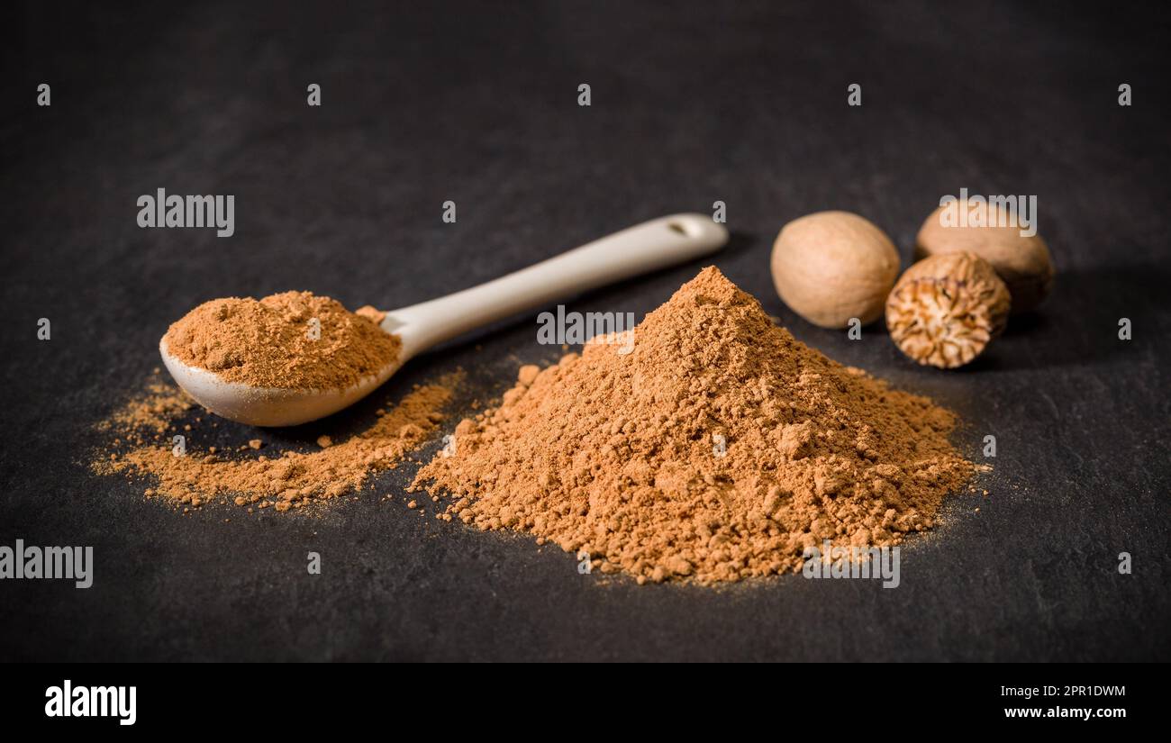 Nutmeg spice powder. Spoon and handful of chopped nutmeg. Nuts. Spices for recipes. Ground spice. Stock Photo