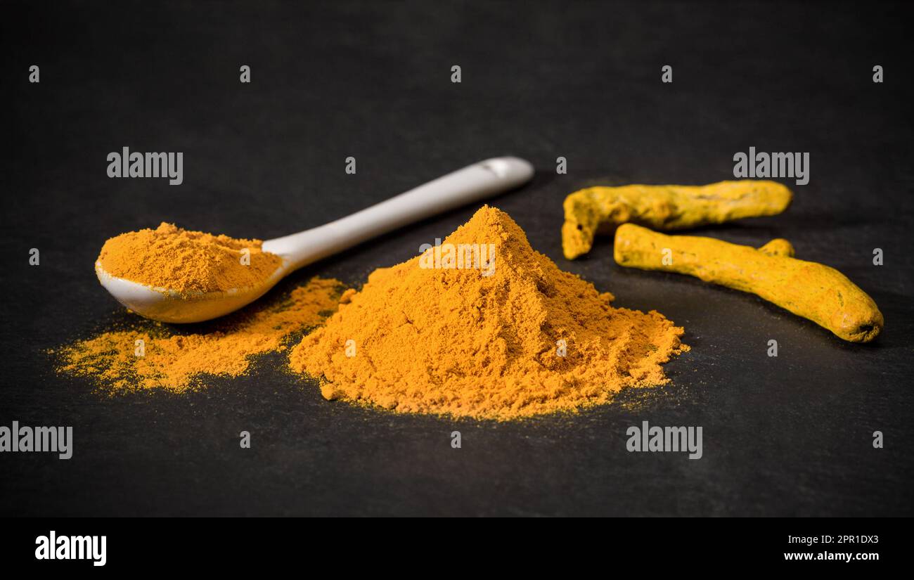Curcuma spice. Spoon and a pile of ground turmeric. Curcuma stick. Spices for curry recipes. Orange Stock Photo