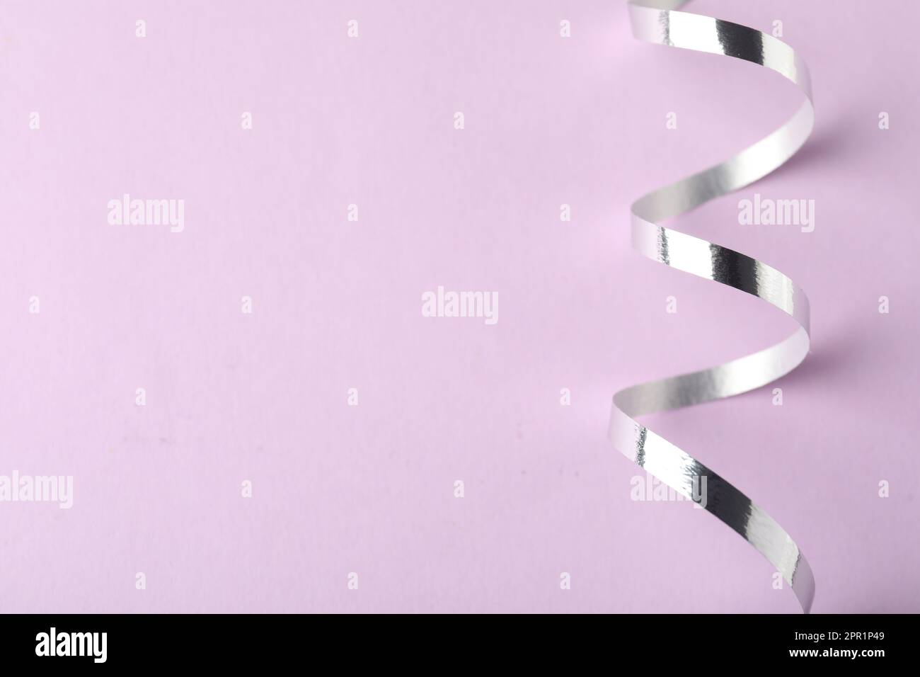 Shiny serpentine streamers on lilac background, closeup Stock Photo - Alamy