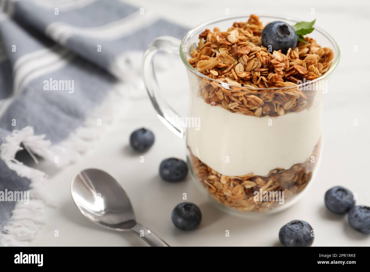 Tasty yogurt with muesli and blueberries served on white table Stock Photo