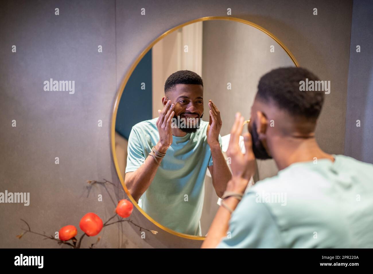 African American man looking at reflection in mirror and smiling Stock Photo