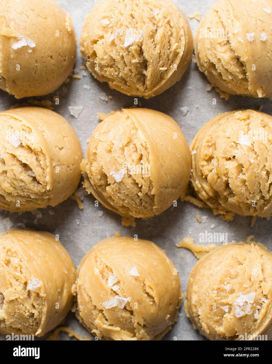 Scooping cookie dough with dough scoop into a baking sheet lined with  parchment paper to bake soft oatmeal raisin walnut cookies Stock Photo -  Alamy