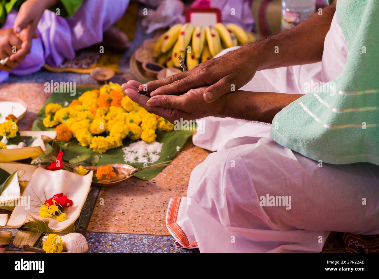 Hindu puja rituals being performed with flowers in front of priest