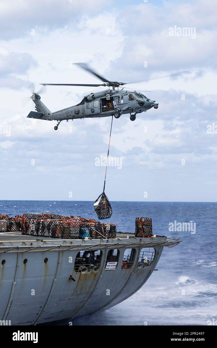 A U.S. Navy SH-60 Seahawk with the Amphibious Assault Ship USS Bataan (LHD 5), lifts supplies while conducting s Resupply At-Sea (RAS) during Amphibious Ready Group/MEU Exercise, Atlantic Ocean, April 22, 2023. The RAS was supported by the USNS Patuxent (T-AO-201), transferring fuel, munitions and supplies to the USS Bataan (LHD 5) while underway. The 26th Marine Expeditionary Unit is underway with the Bataan ARG as part of it’s Pre-deployment Training Program. (U.S. Marine Corps photo by Cpl. Kyle Jia) Stock Photo