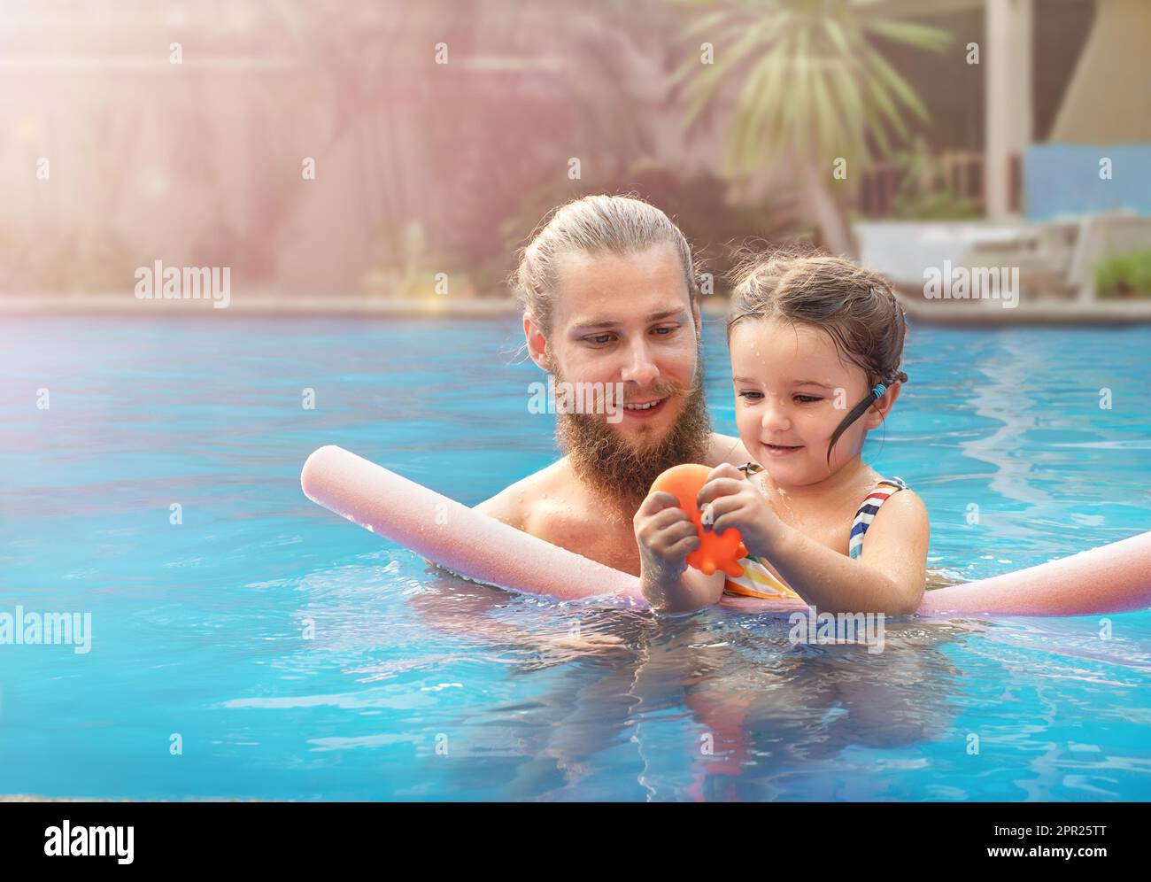 Dad and daughter playing with a ball in the pool Stock Photo