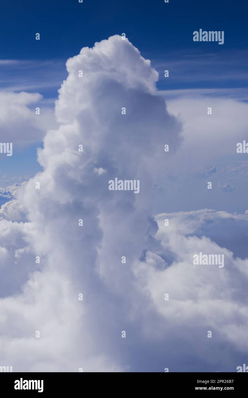 Cumulus and cumulonimbus rain clouds seen from aeroplane. Shot taken in flight against blue sky