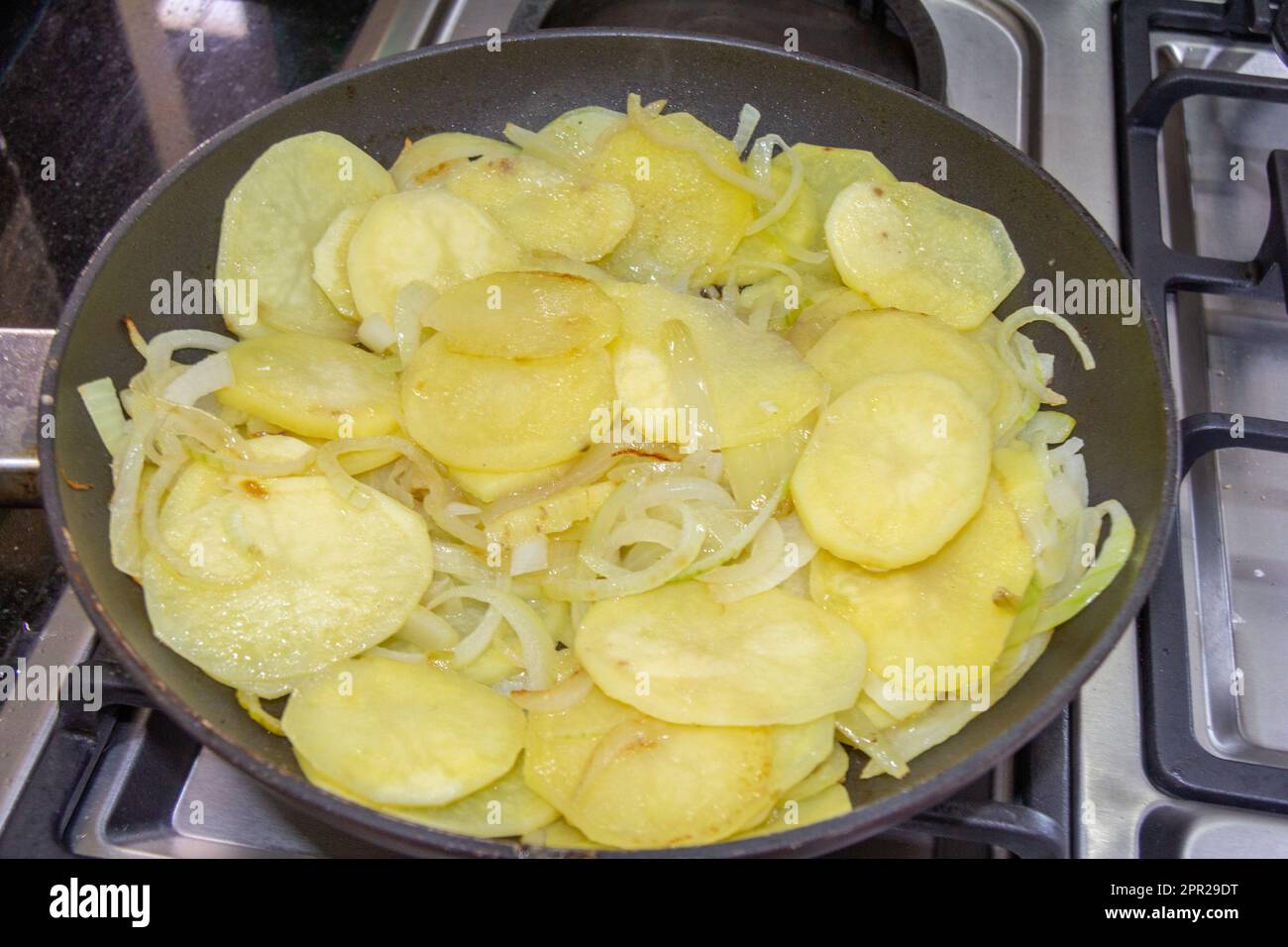 Frying a Spanish omelette or tortilla on a gas powered hob. Stock Photo