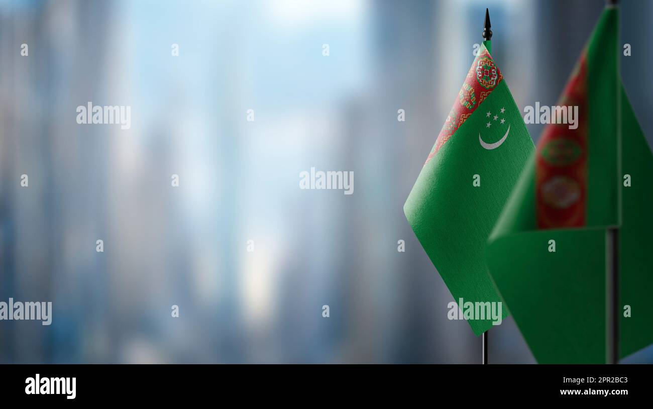 Small flags of the turkmenistan on an abstract blurry background stock