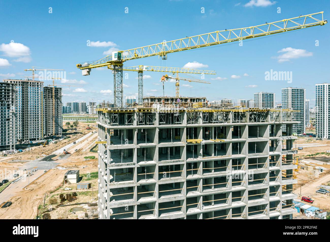 cranes building new residential houses on a building site against the blue sky. aerial closeup view. Stock Photo