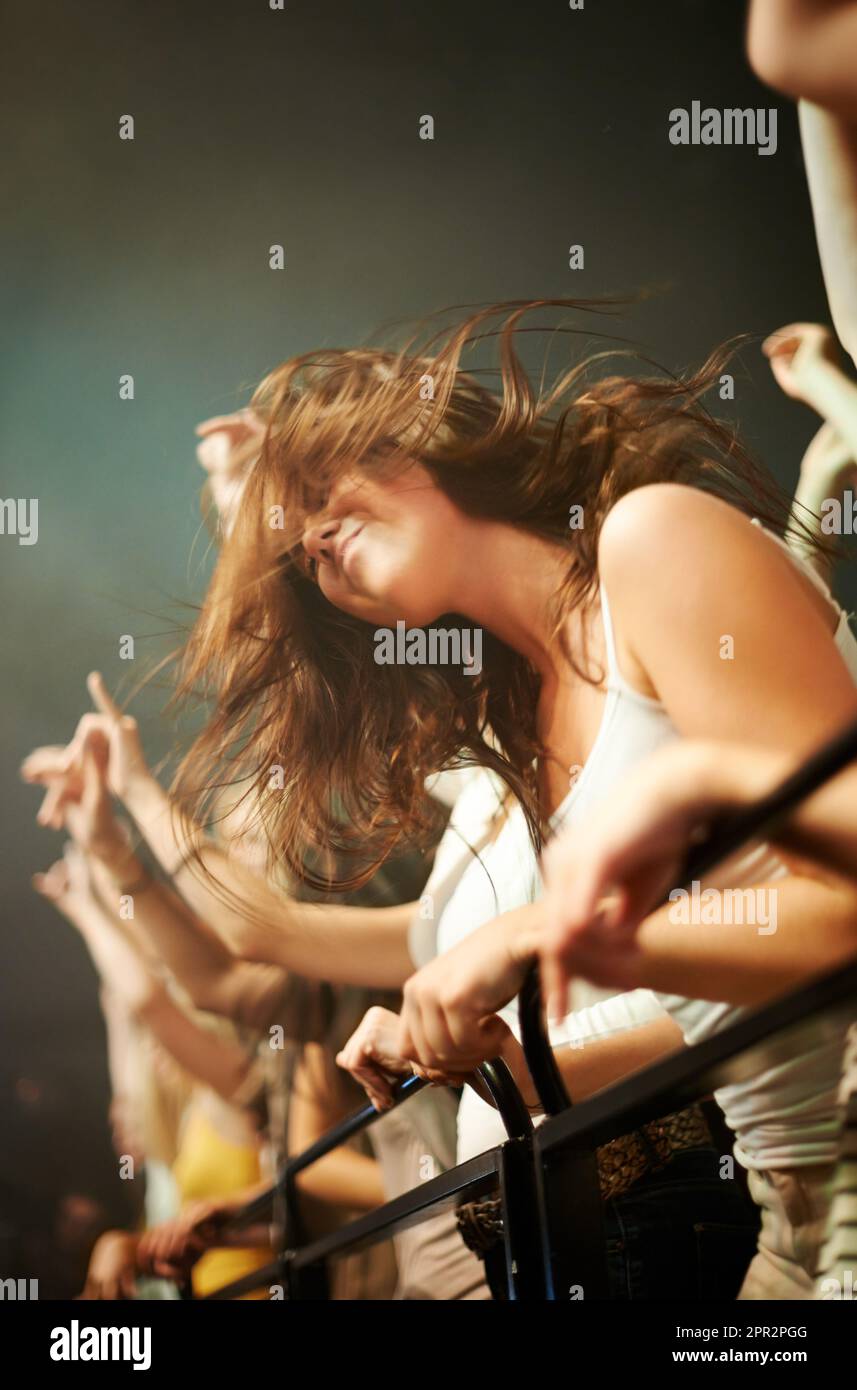 Fence, dancing and woman in crowd at concert or music festival, happiness at rock event. Girl in audience, excited fan at live band performance in Stock Photo