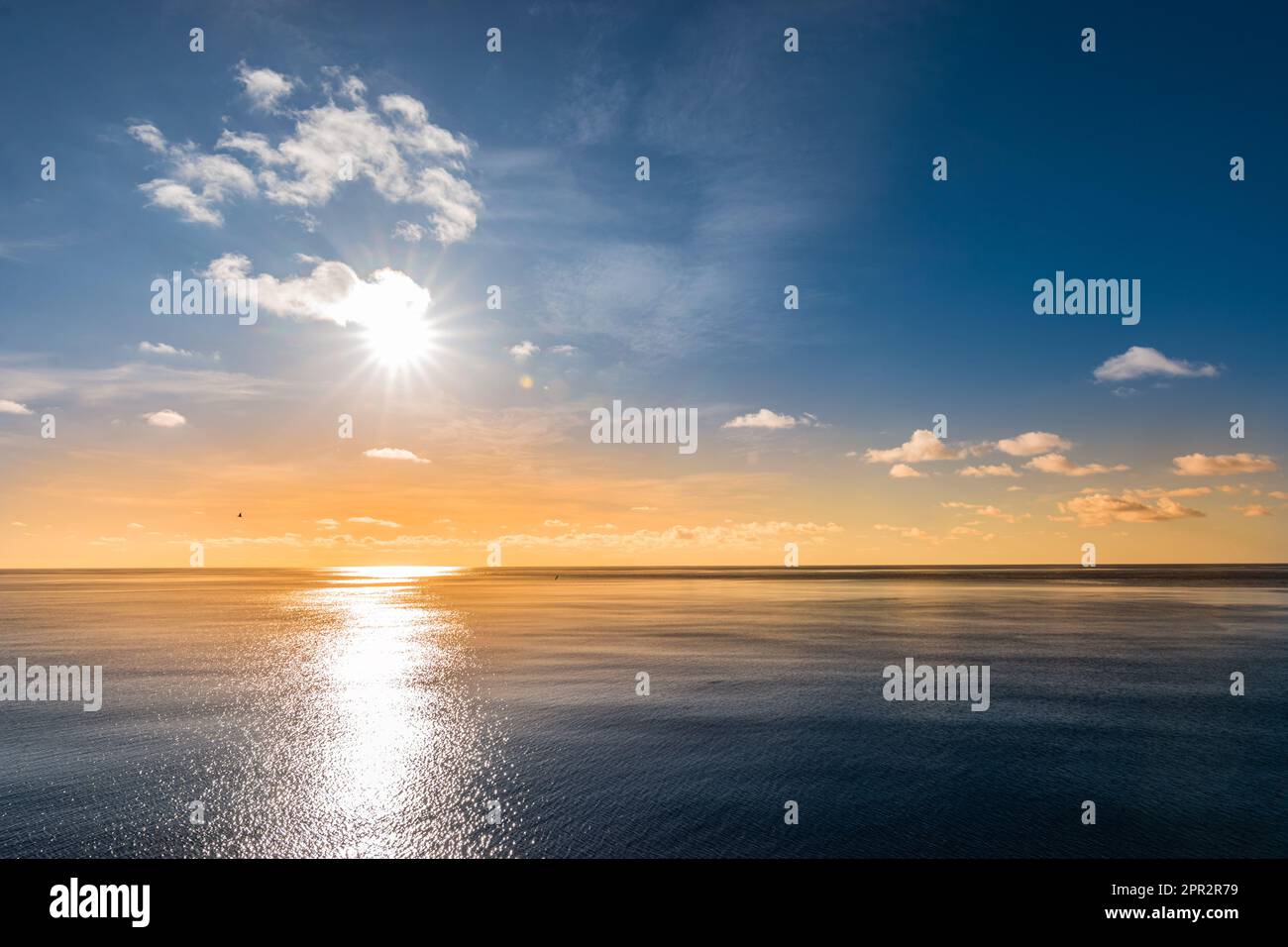 Colorful orange sunset sky with reflection of the sun in the sea. Stock Photo