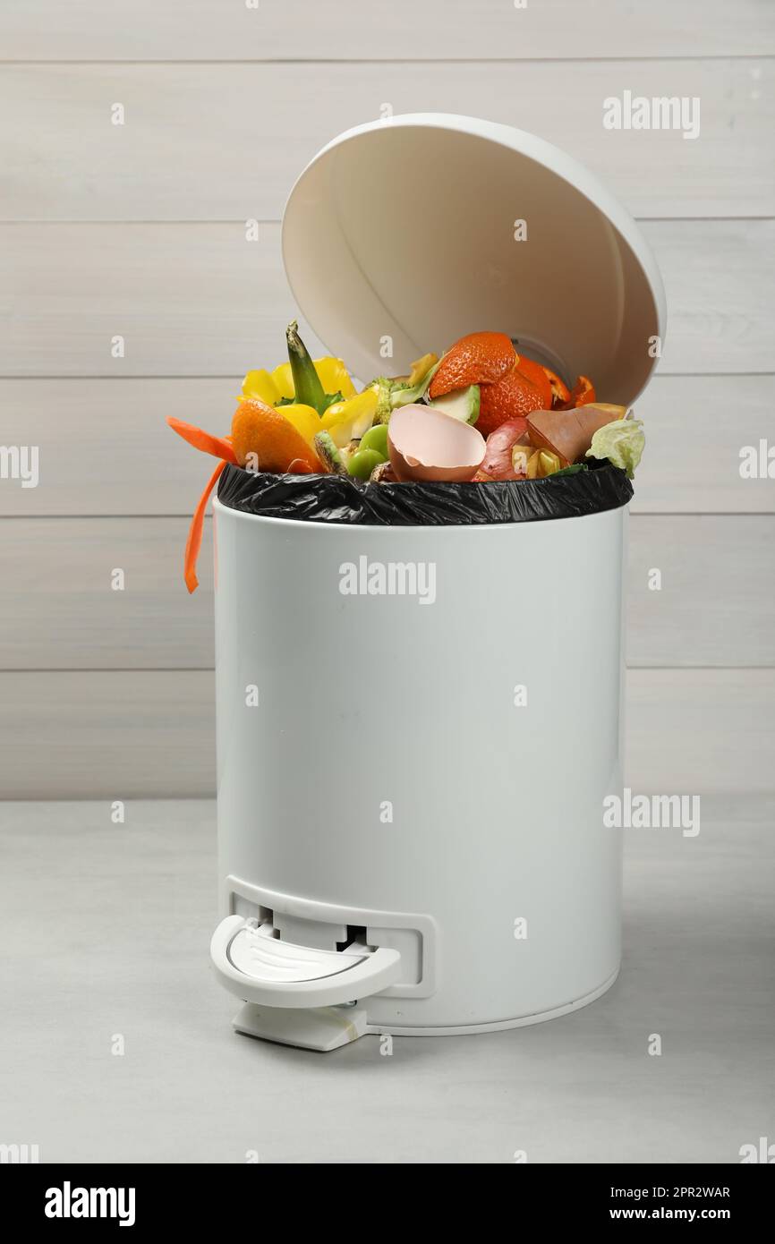 Trash bin with organic waste for composting on light background Stock ...