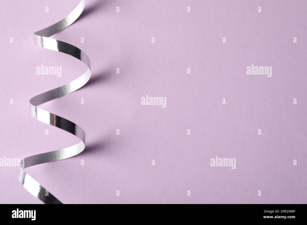 Shiny serpentine streamers on lilac background, closeup Stock Photo - Alamy