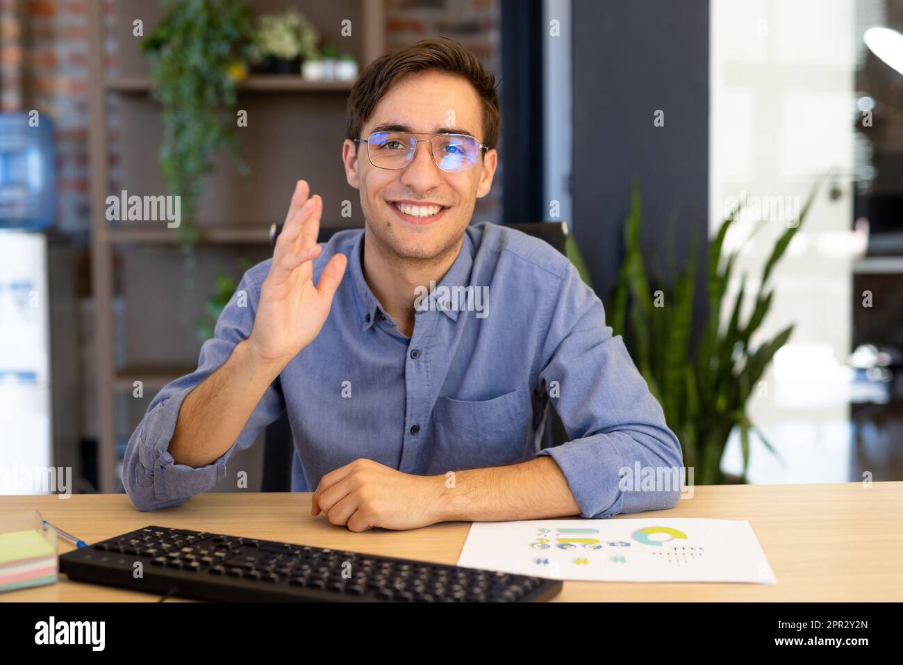 Portrait of happy caucasian casual businessman making video call, smiling and waving Stock Photo