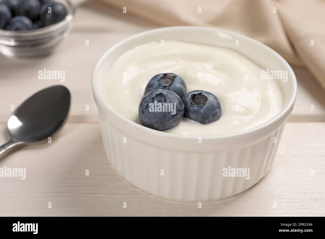 Bowl of yogurt with blueberries served on white wooden table, closeup Stock Photo