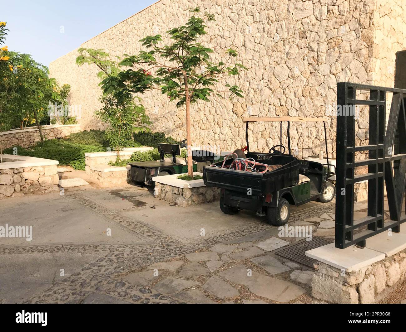 A small electric car, an electro golf card environmentally friendly to deliver people green on the background of an old, antique stone wall. Past and Stock Photo