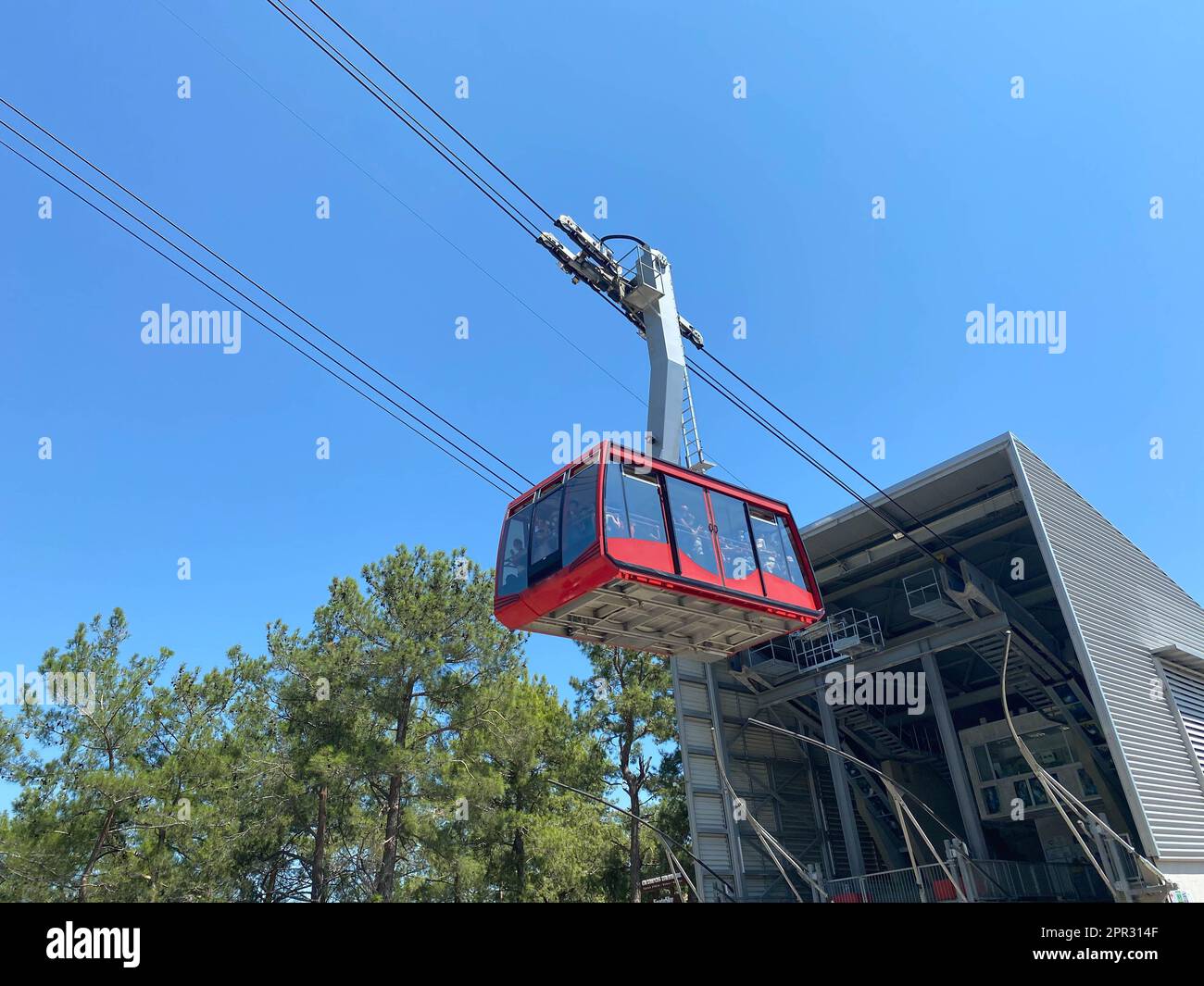 Red modern tourist cabin of the cable car ascends the mountains against ...