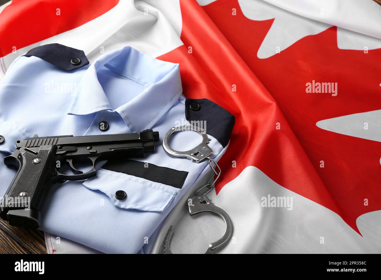 Policeman's uniform with gun, handcuffs on flag of Canada, closeup