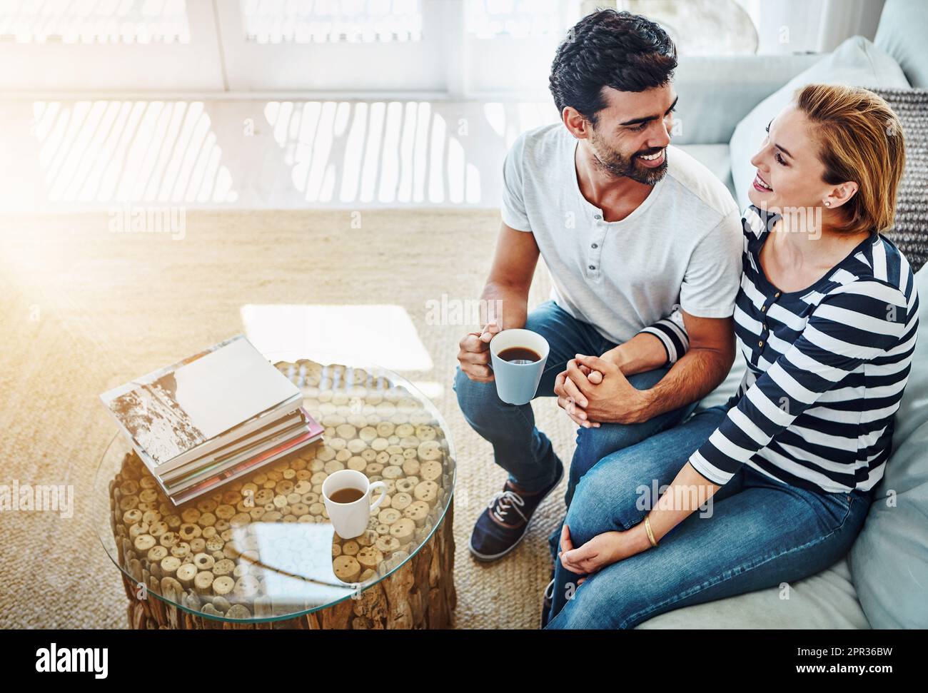 Getting closer with every passing moment. High angle shot of an affectionate young couple having coffee together at home. Stock Photo