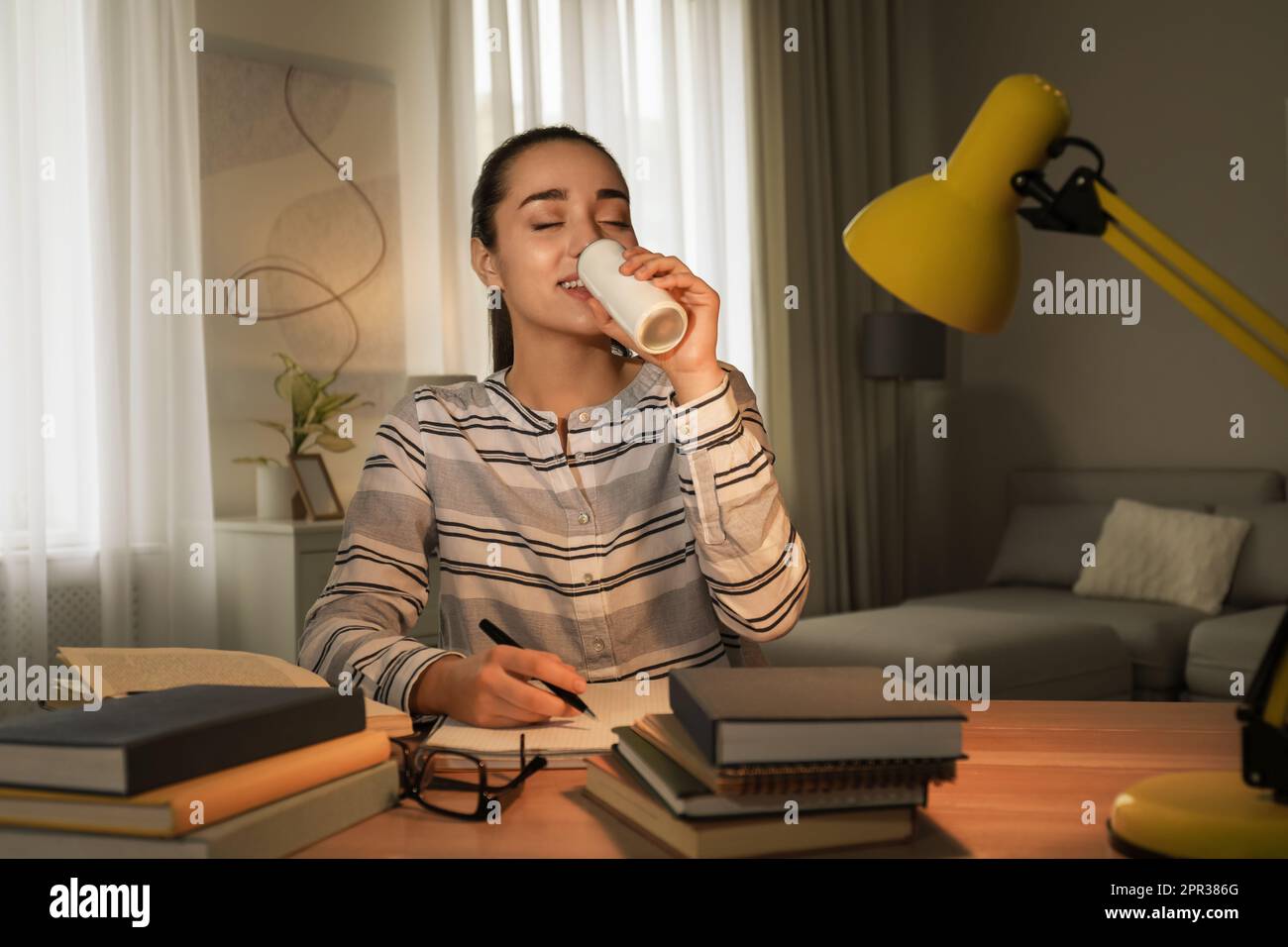 Young woman with energy drink studying at home Stock Photo Alamy