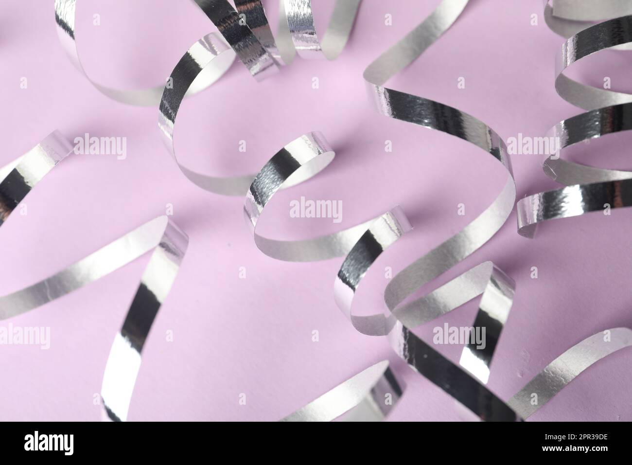 Shiny serpentine streamers on lilac background, closeup Stock Photo - Alamy