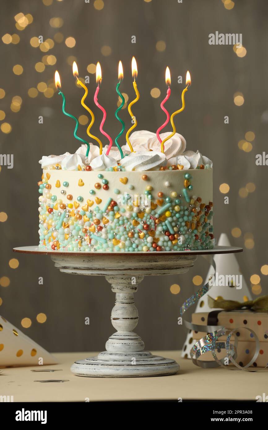 Beautiful birthday cake with burning candles and decor on white table ...