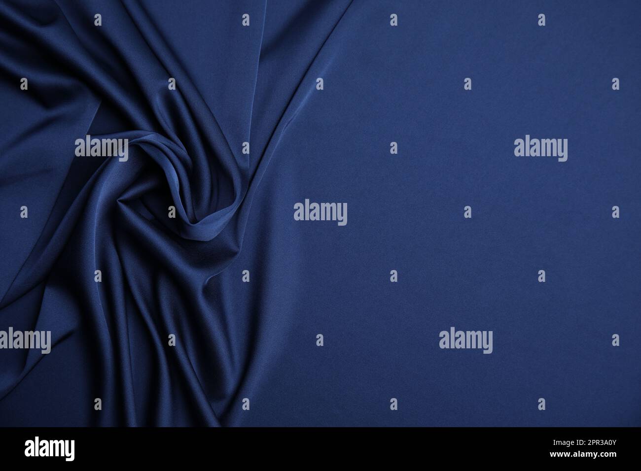 Crumpled dark blue silk fabric as background, top view. Space for text ...