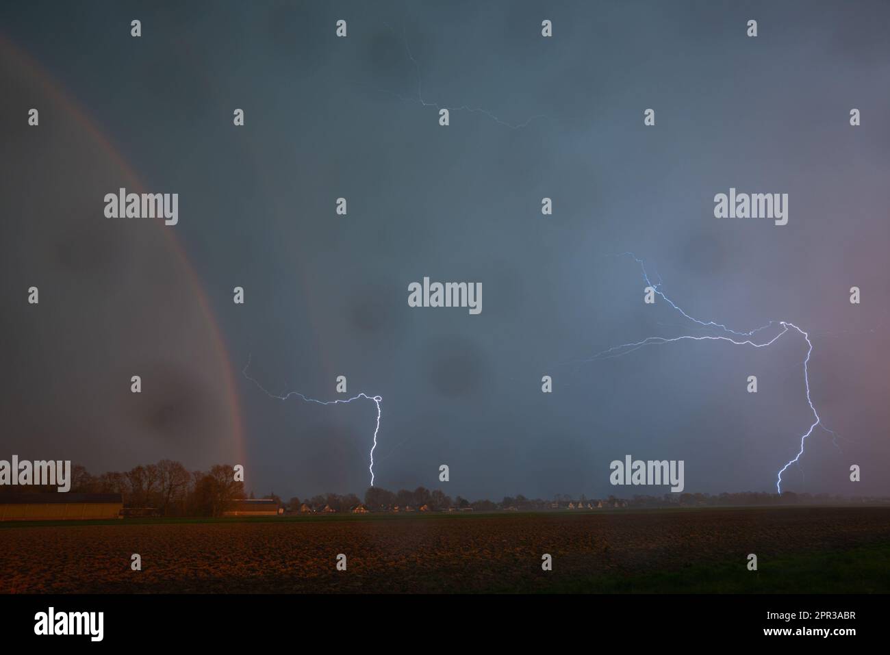 Lightning storm with rainbow. Raindrops on the lens. Stock Photo