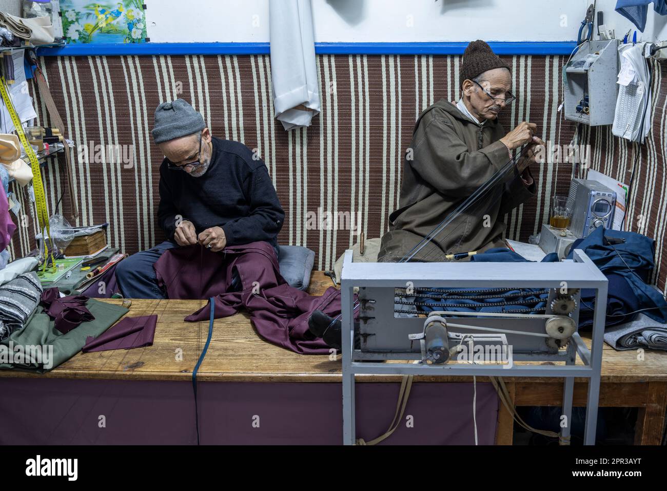 Men sewing djellabas by hand in a small workshop in the kasbah of Tangier. Stock Photo