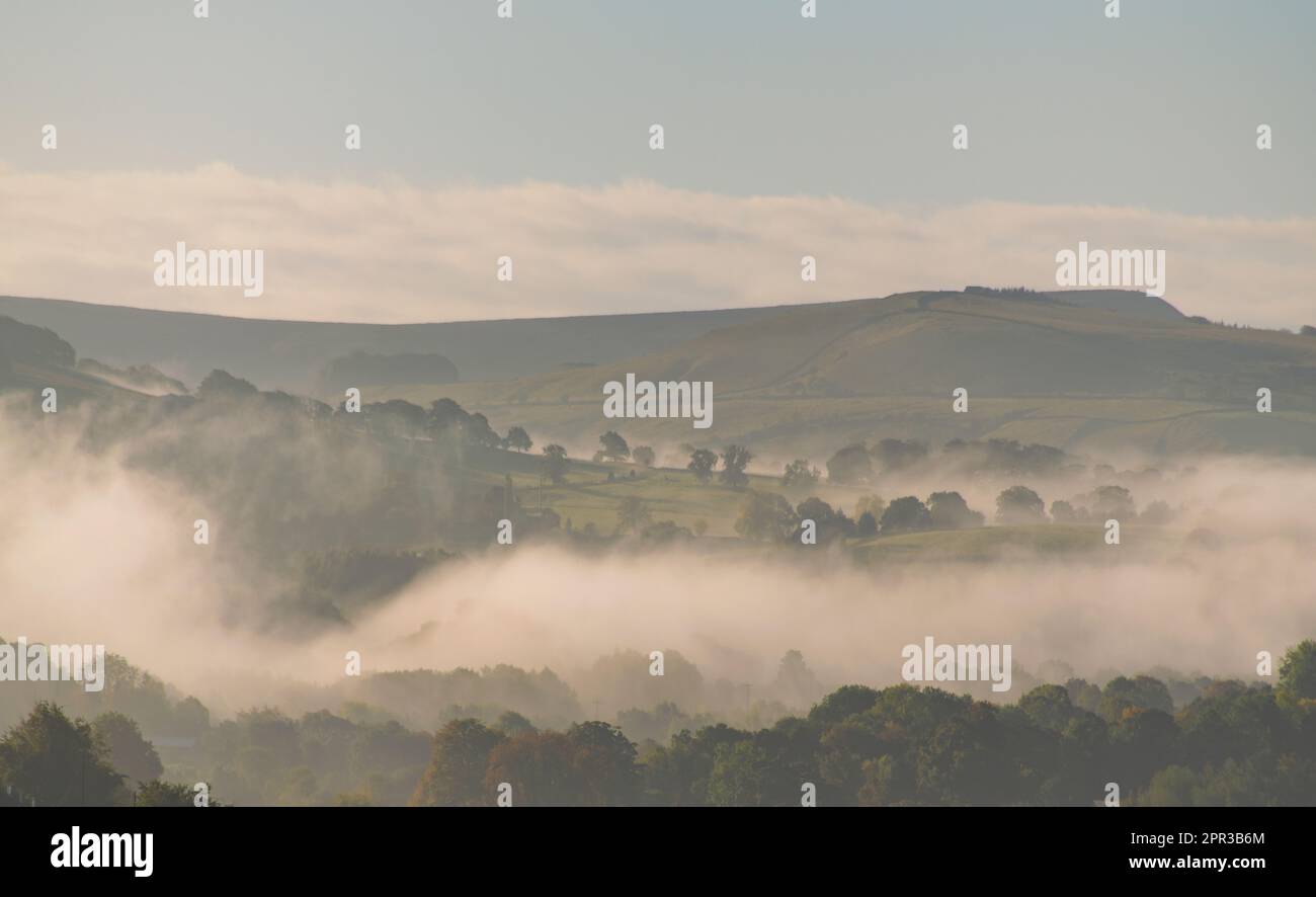 A misty morning with fog in the valleys in the English Peak District, clouds around the trees caused by a temperature inversion on an early autumn day Stock Photo