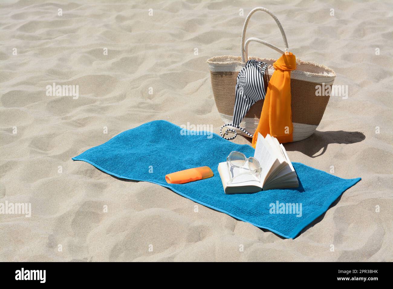 Blue towel, bag and beach accessories on sand Stock Photo - Alamy