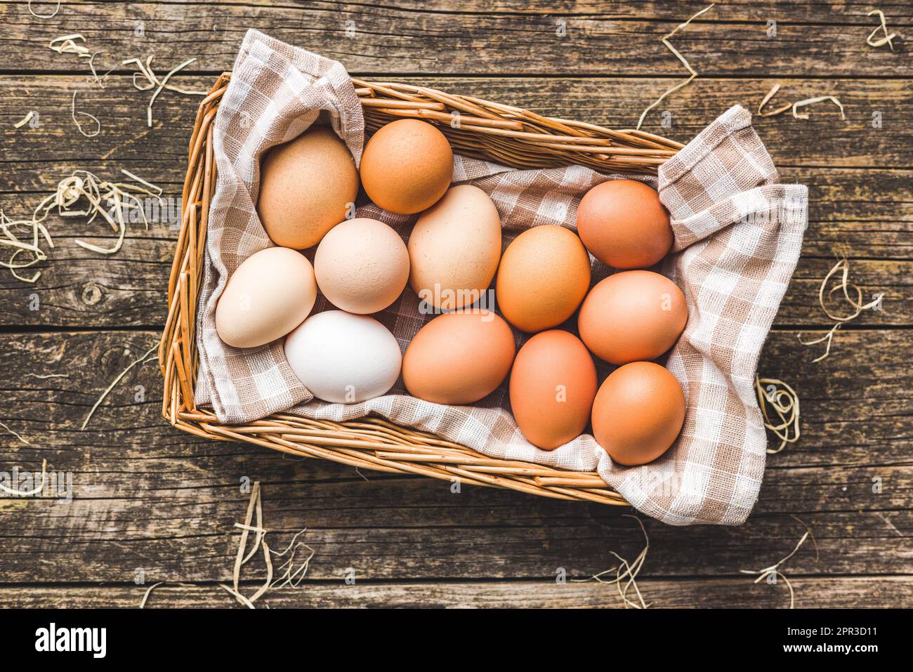 Whole chicken eggs in basket on the wooden table. Top view. Stock Photo
