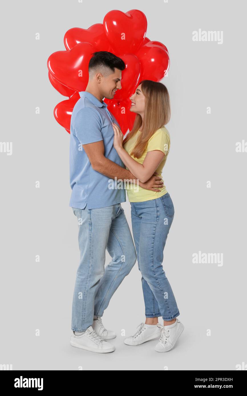 Lovely couple with heart shaped balloons on light grey background ...