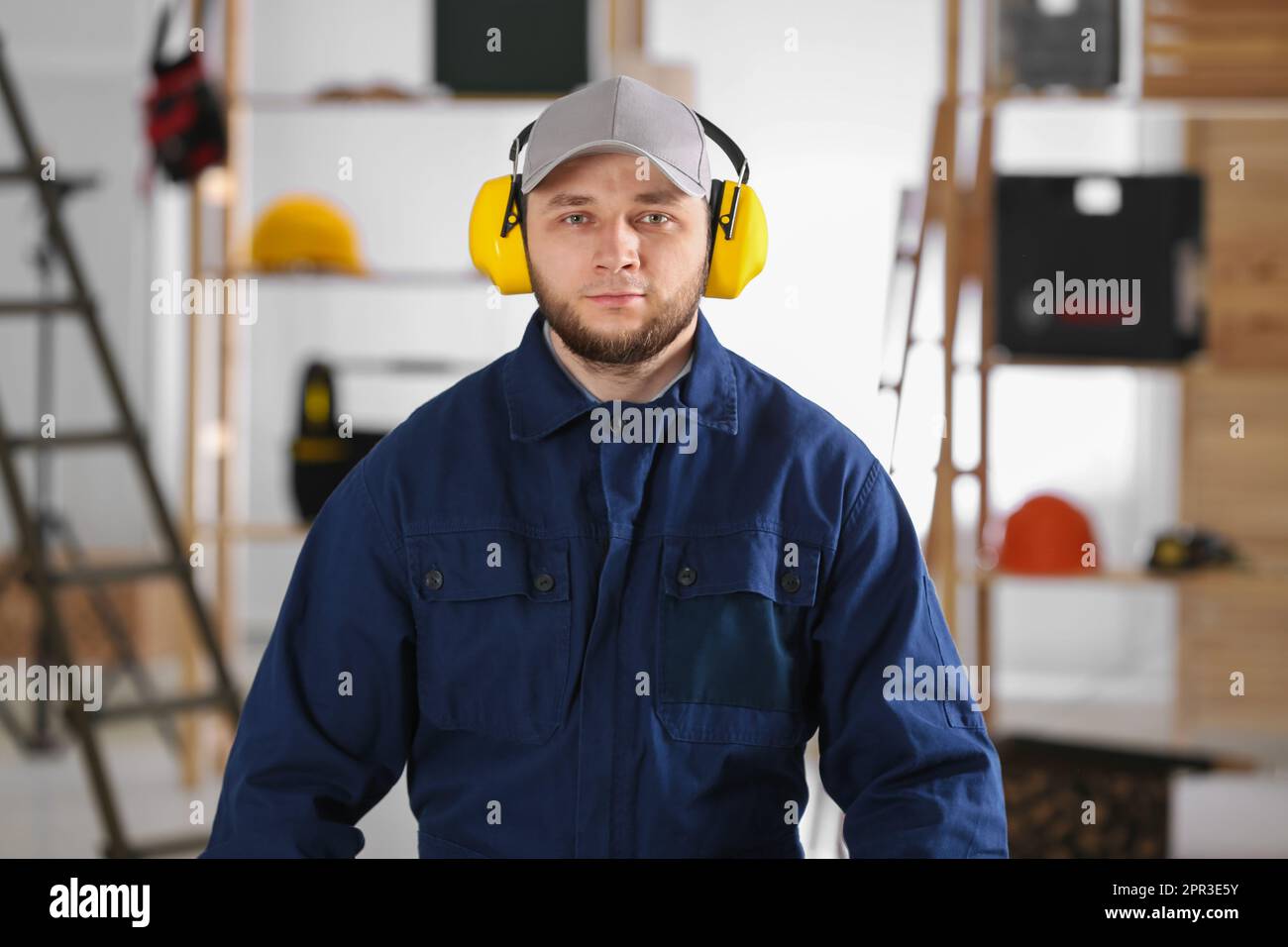 Worker wearing safety headphones indoors. Hearing protection device