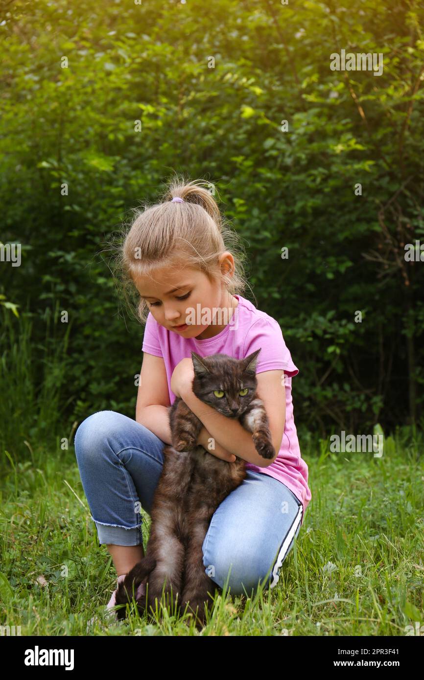 Cute little girl with cat in green park Stock Photo - Alamy