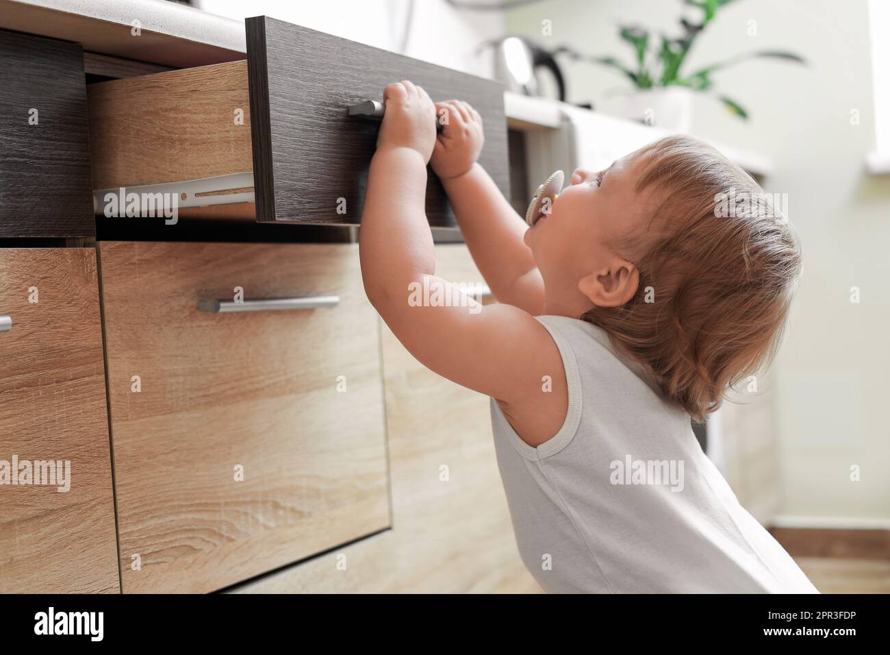 Little child exploring drawer indoors. Dangerous situation Stock Photo