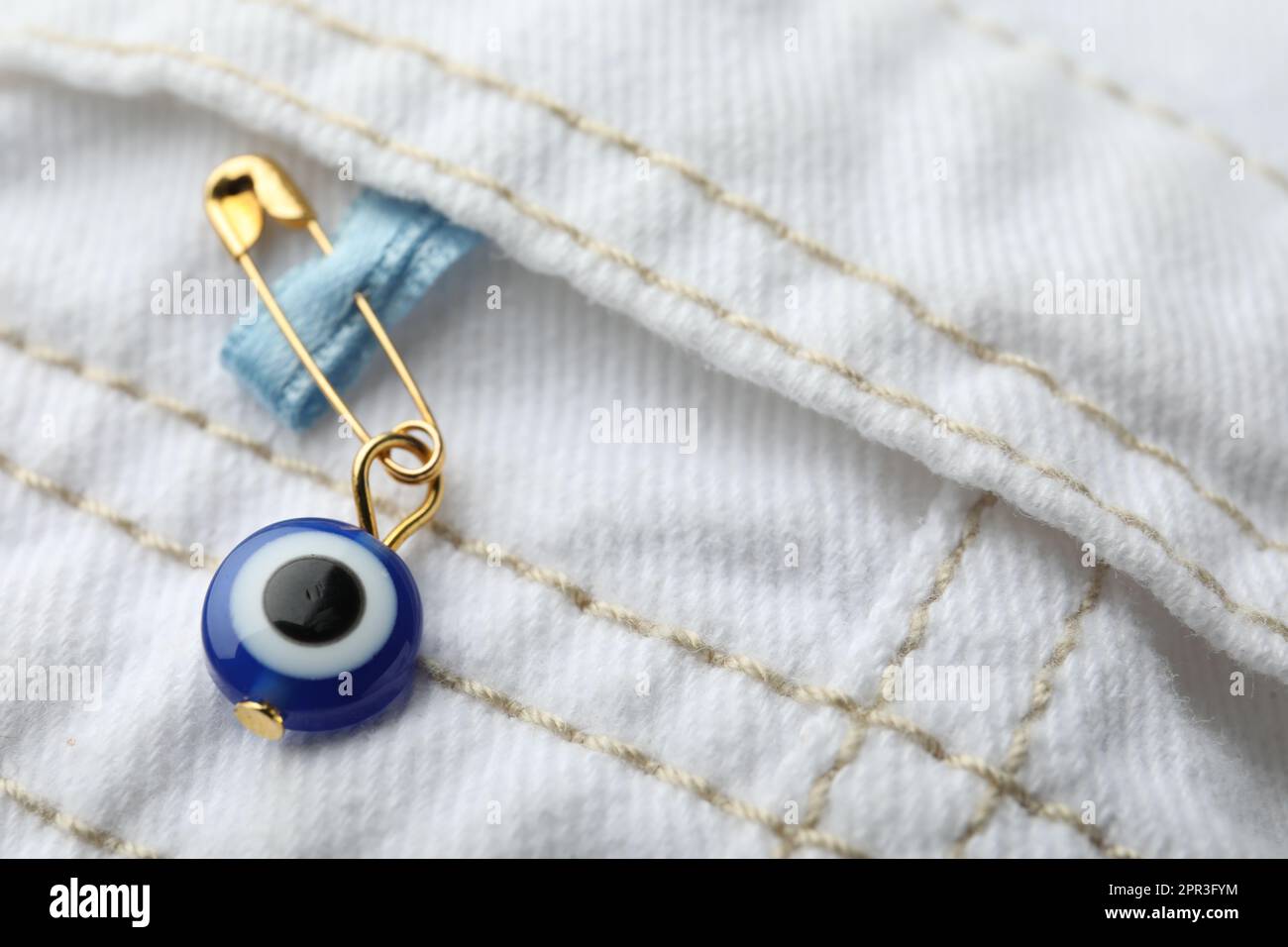 Evil eye safety pin on clothing, closeup Stock Photo - Alamy