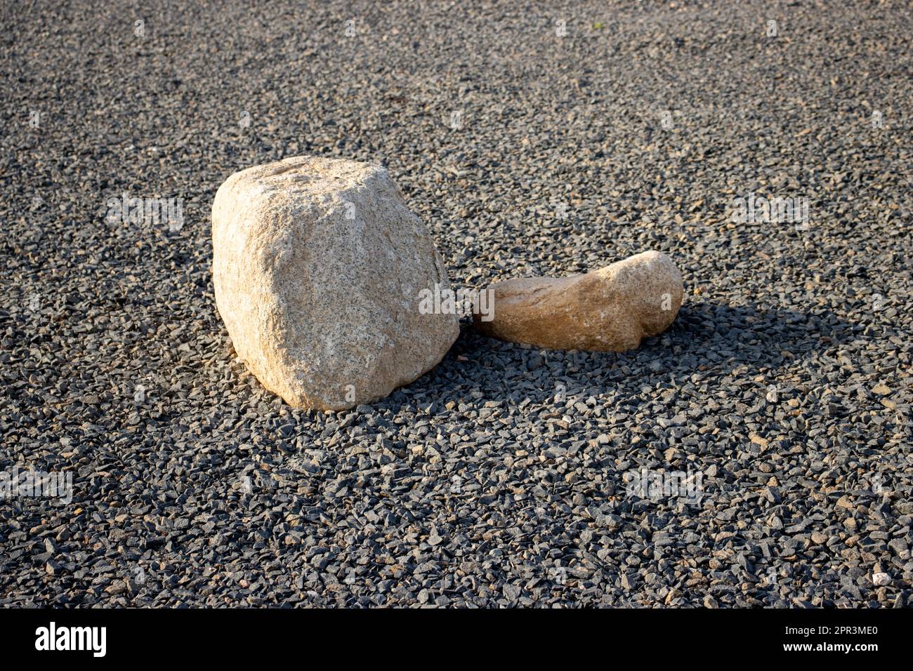 two white rocks on a black bed of rocks Stock Photo - Alamy