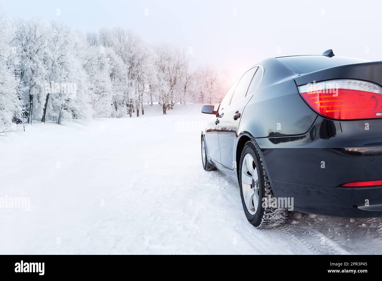 Black car on a winter road in a snowy forest, winter journey. Modern