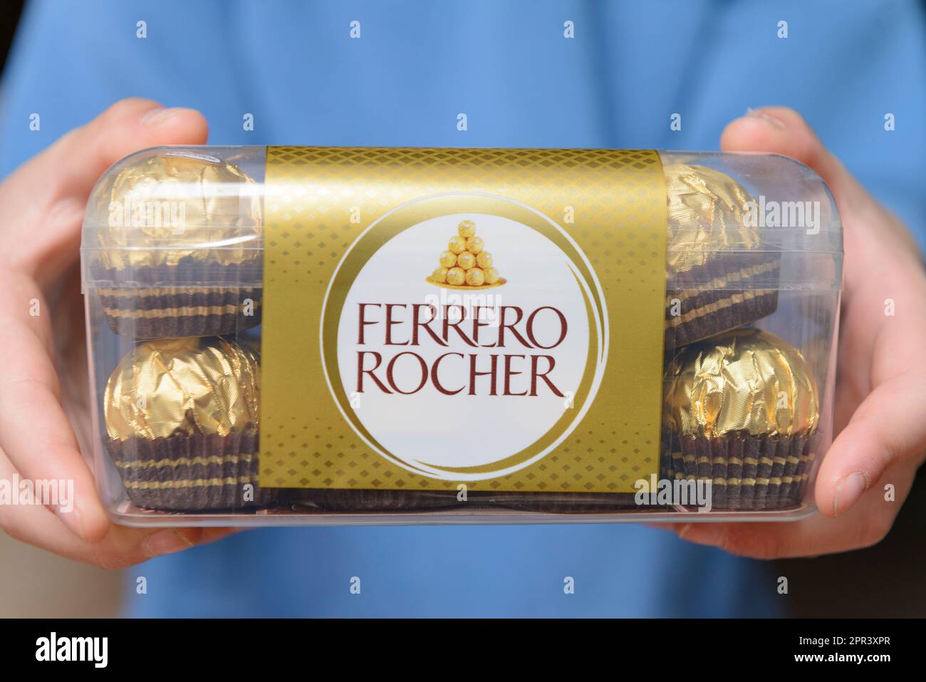 Arahal. Seville. Spain. March 18, 2023. Closeup of a child's hands holding a box of chocolates of Ferrero Rocher. Excessive consumption of sugar can h Stock Photo