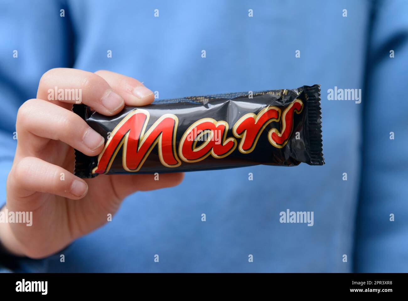 Arahal. Seville. Spain. March 18, 2023. Close-up of a child's hands holding a candy bar from the brand Mars. Excessive consumption of sugar can have n Stock Photo