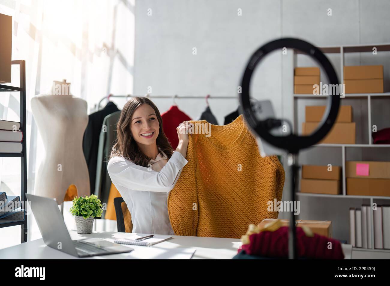 Young lady fashion designer using mobile phone showing clothes recording video live streaming online at shop. Small business owner online market Stock Photo Alamy