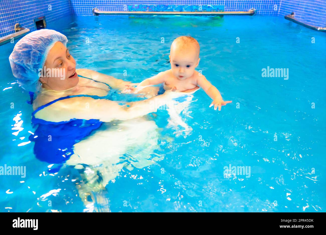 Adorable baby girl enjoying swimming in a pool with her mother early development class for