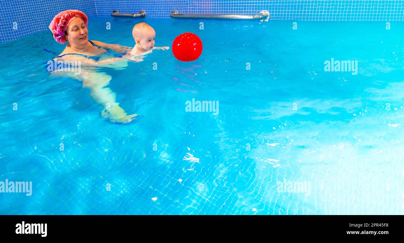 Adorable baby girl enjoying swimming in a pool with her mother early development class for