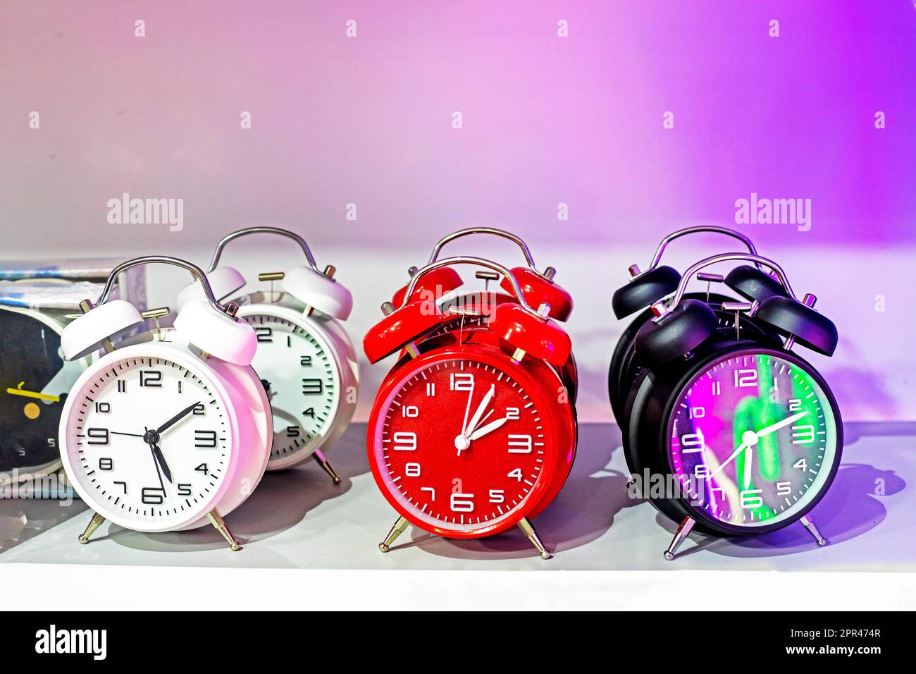 alarm clocks watch white red and black lights in bright pink lighting. Change time to summer or winter Stock Photo