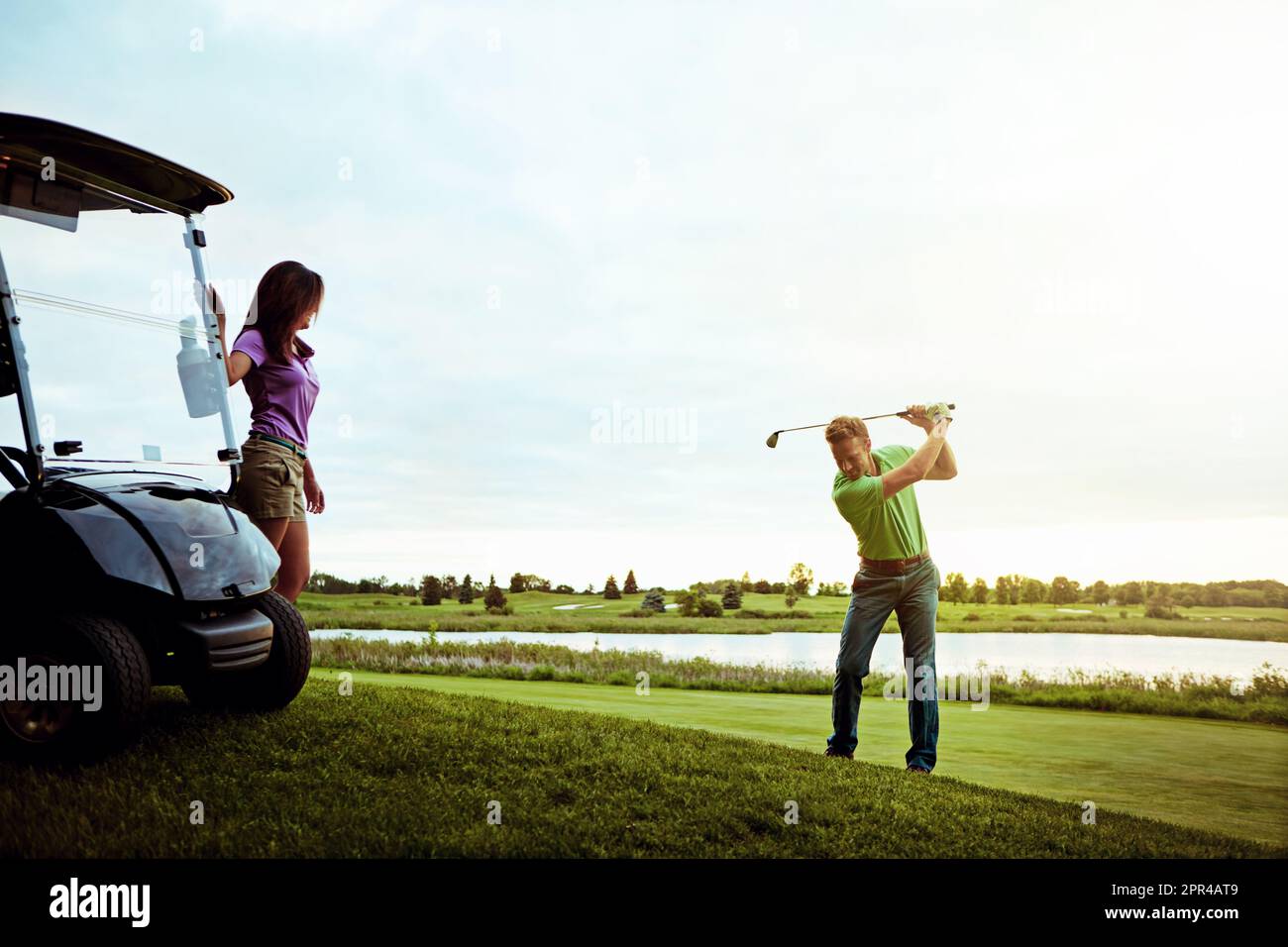 Nice form, babe. a man practicing his swing on the golf course. Stock Photo