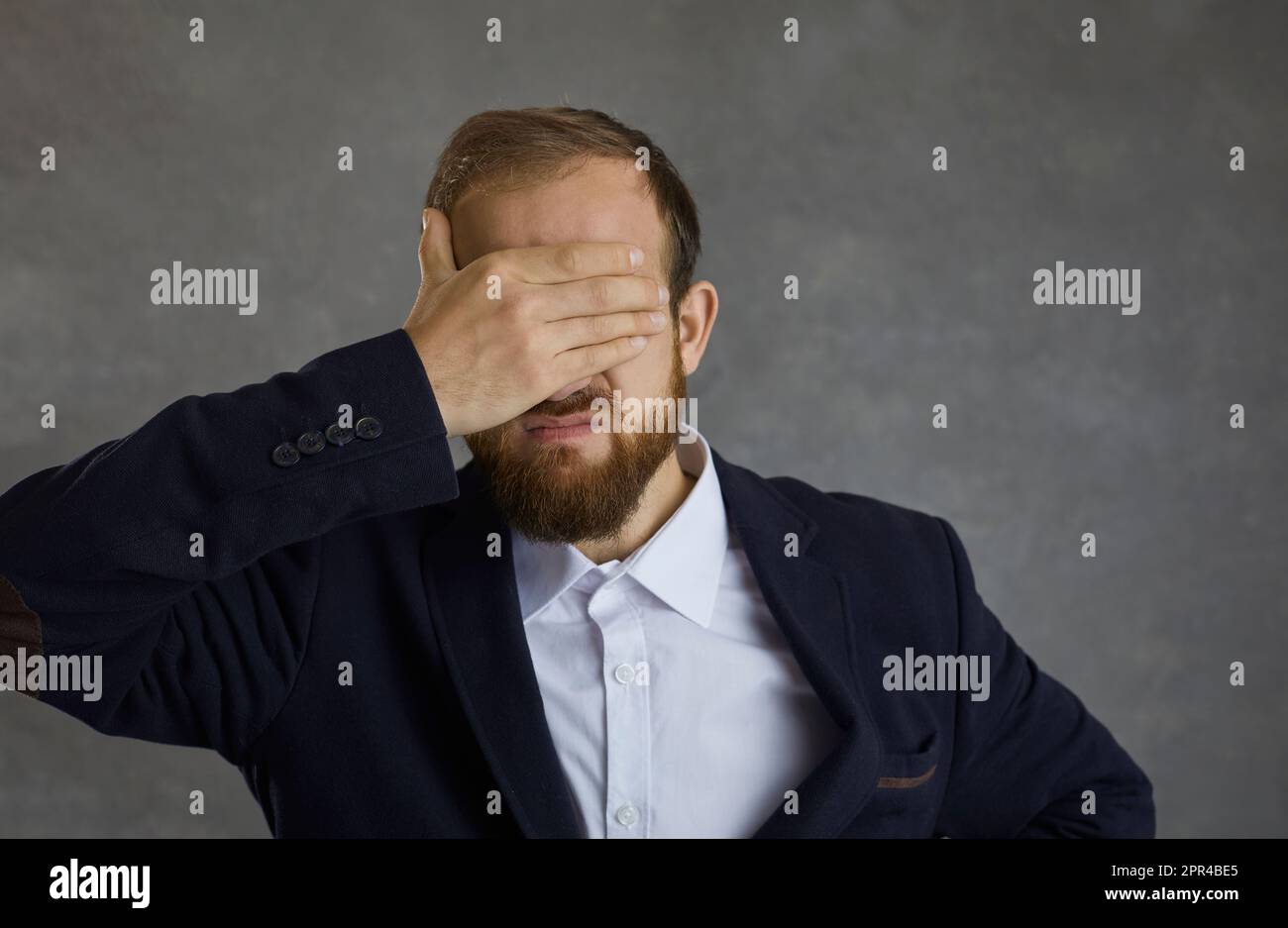 Frustrated businessman closes his eyes with his hand, not wanting to see anything or anyone. Stock Photo