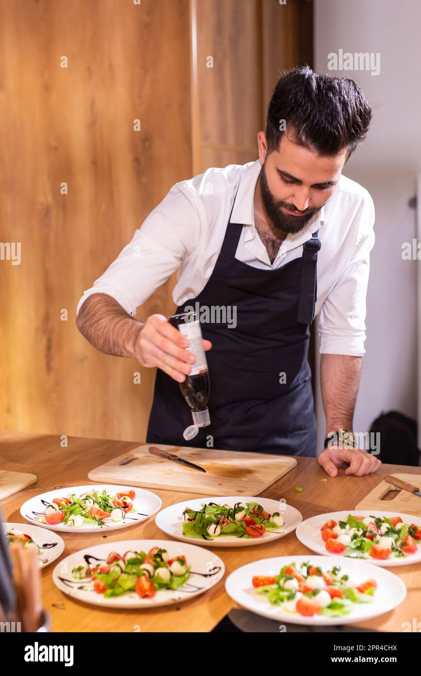 Chef pouring dressing over caprese salad in restaurant kitchen Stock ...