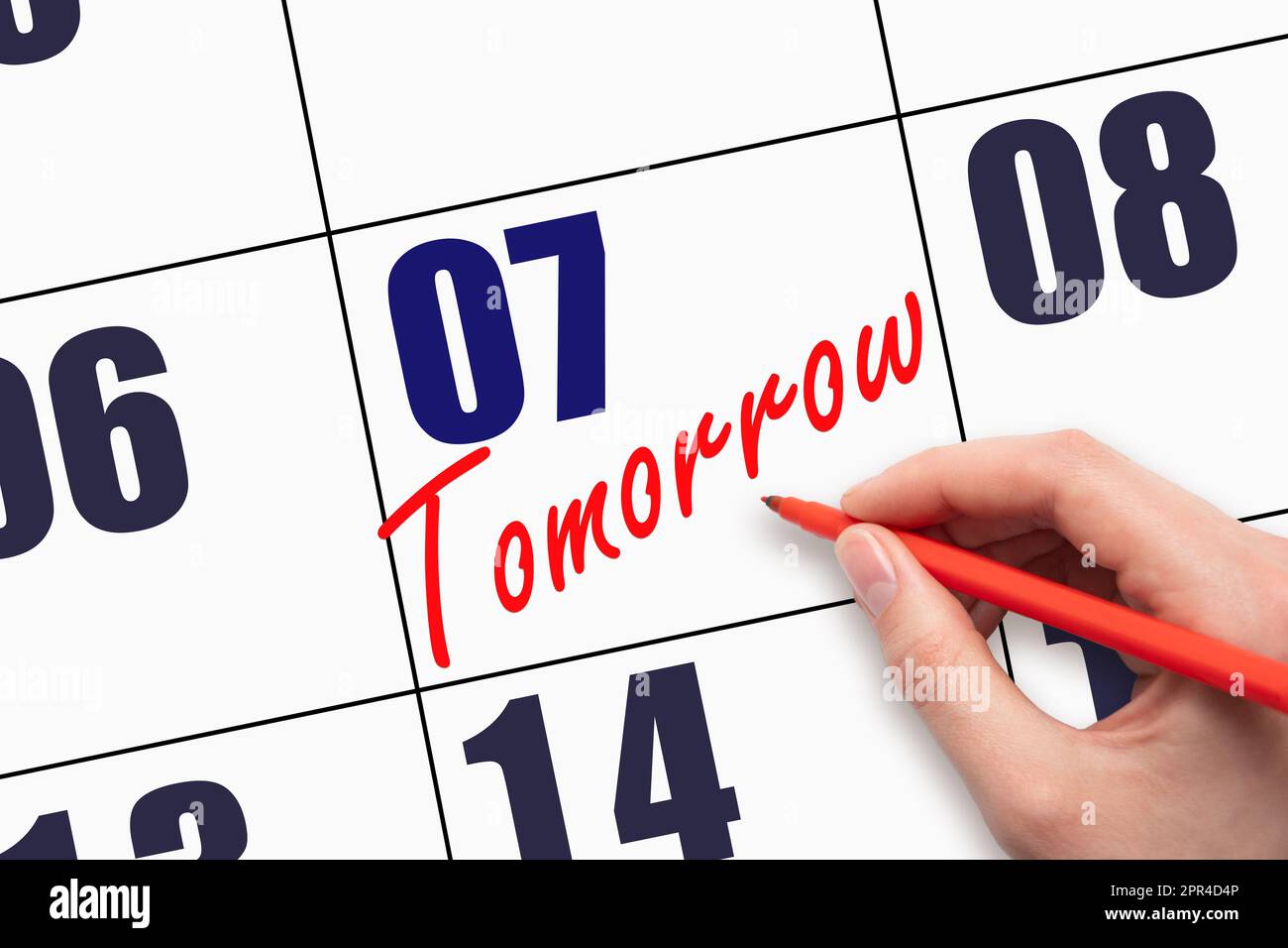 7th day of the month. Hand writing text TOMORROW on calendar date ...