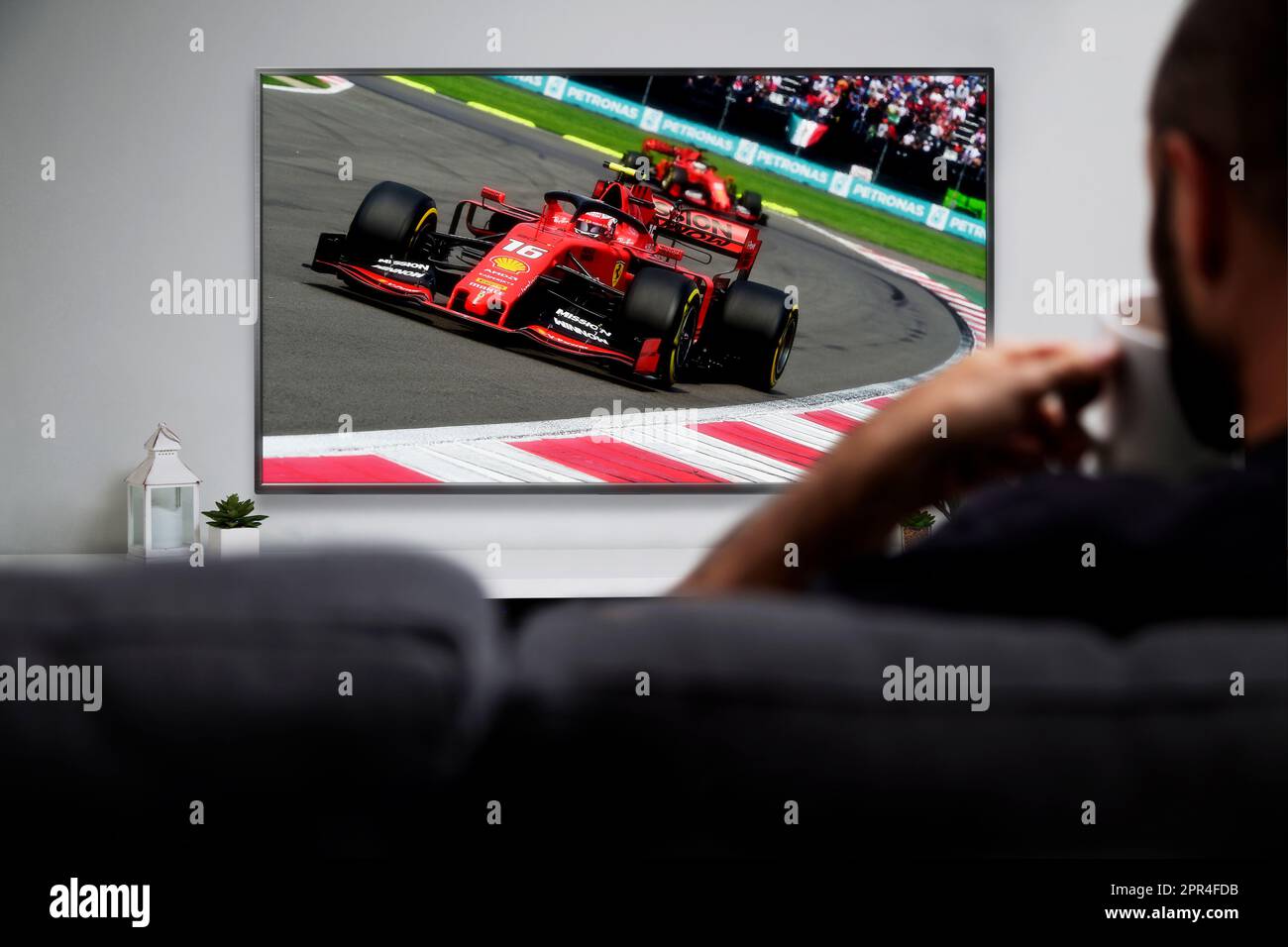 Man watching formula racing on smart TV. Live racing transmission